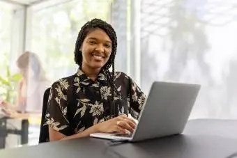 Mulher jovem sorridente sentada na mesa de escritório