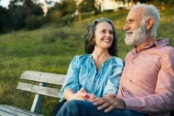Homem e mulher sorrindo e sentados em um banco