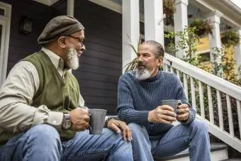 Пожилые мужчины пьют кофе перед загородным домом