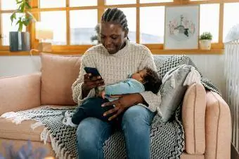 mamma håller sovande baby på telefonen