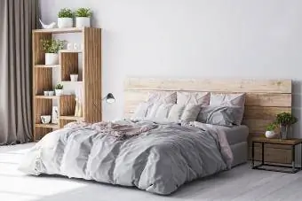 Coin chambre confortable dans un appartement en bois avec lit confortable en bois et plantes vertes.