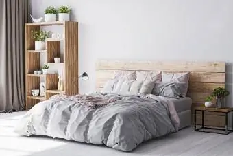 Acogedora zona de dormitorio en un apartamento de madera con una cómoda cama de madera y plantas verdes.