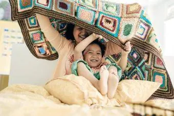 Mama și fiul jucând împreună sub pătură de croșetat