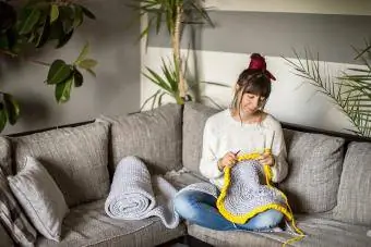 Млада жена плете на една кука в хола