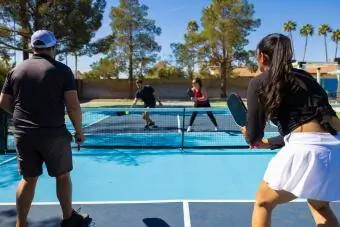 En gruppe på fire spiller double pickleball på en solskinsdag