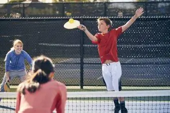 Batang lalaki na naglalaro ng pickleball kasama ang pamilya