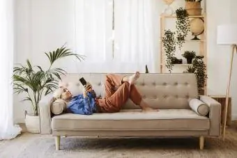 Wanita muda berbaring di sofa di rumah