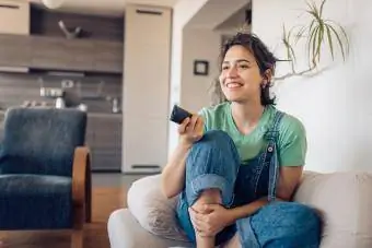 زن جوان در حال لذت بردن از برنامه تلویزیونی مورد علاقه خود در خانه