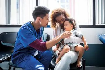 Mužská sestra zkoumá holčičku se stetoskopem v nemocnici
