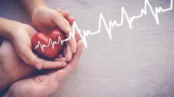 drží červené srdce s kardiogramom