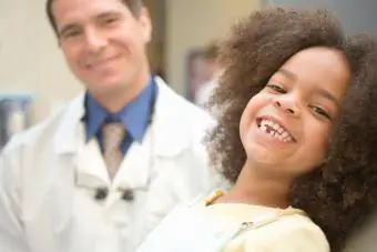 шүдний эмчийн сандал дээр инээмсэглэж буй охин