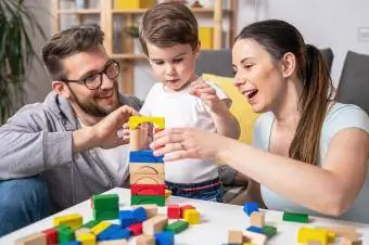 Madre e padre che giocano con il bambino utilizzando giocattoli didattici in legno