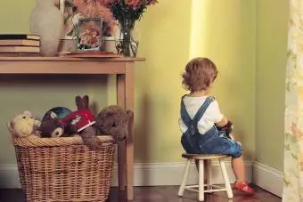 Jeune enfant assis dans un coin en guise de punition