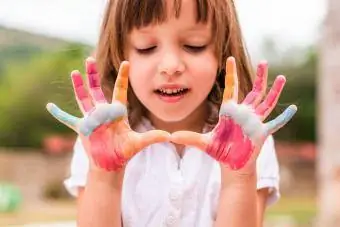 Menina bonitinha com mãos coloridas