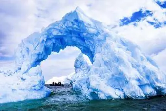 Et isbjerg af blå is i Antarktis med et interessant hul