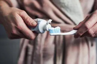 Vrouw die tandpasta op een tandenborstel zet