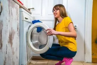 mulher usando uma máquina de lavar para lavar roupa em casa