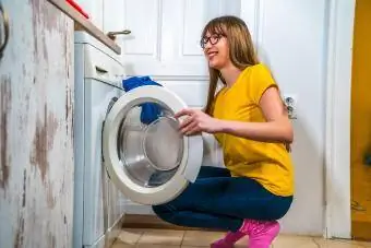 vrou wat 'n wasmasjien gebruik om wasgoed by die huis te was