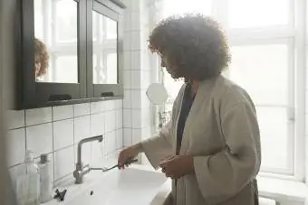 Moteris plauna dantų šepetėlį po tekančiu vandeniu