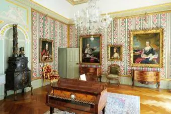 Victoriaanse sitkamer met portrette teen die mure en 'n stoof