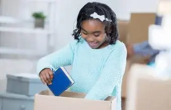 dívka balí knihy v kartonové krabici