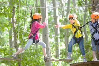 Niños felices jugando en el parque de aventuras en las copas de los árboles