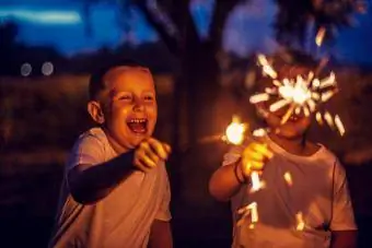 Meninos se divertem no parque com brilhos de fogos de artifício