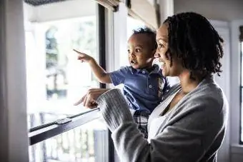 Majka i malo dijete gledaju kroz prozor kuće