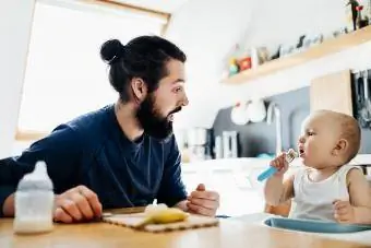 Otec pomáha dieťaťu jesť obed