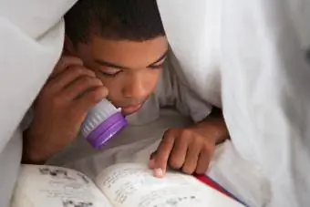 Junge liest Buch unter Decke