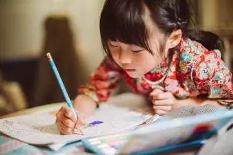 लड़की ख़ुशी से रंग भरने वाली किताब में रंग भर रही है