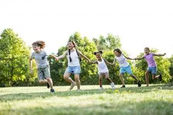 Dzieci trzymające się za ręce i biegające w parku