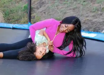 Mamá usando ropa deportiva mientras juega en un trampolín con su hija