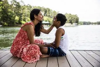 Maman portant une robe longue assise sur le quai avec son fils