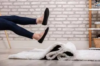 Женщина сидит и поднимает каблуки в воздух в черных туфлях на плоской подошве