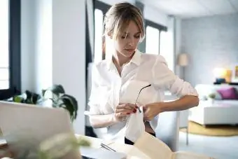 femeie care își curăță ochelarii pe cămașă