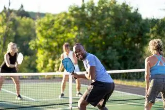 Man ler mot kameran medan han spelar pickleball