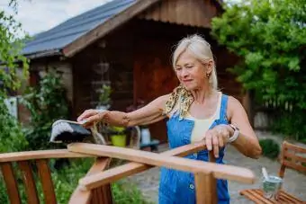 Senior kvinde skrubber udendørs teakmøbler