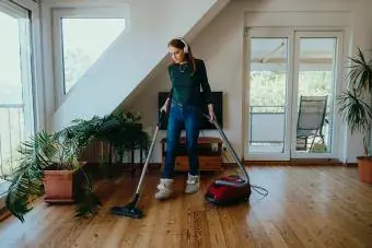 wanita membersihkan lantai kayu dengan vakum