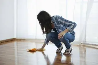 Wanita mengelap lantai kayu dengan kain microfiber