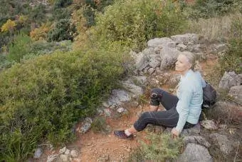 Mujer excursionista descansa sobre el sendero