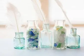 Bocaux en verre bleu remplis de verre de mer et de plumes blanches