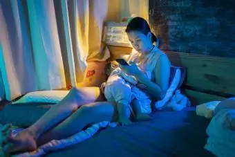 Žena krmení dítěte a sledování telefonu