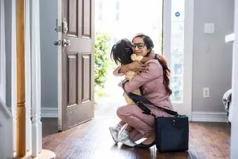 Nena petita abraçada a la mare a la porta