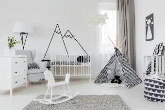 Kinderkamer met wit meubilair, tapijt, tent en bergmuursticker