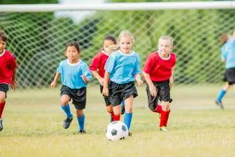 Isang grupo ng mga bata ang nasa soccer field na naglalaro ng laro