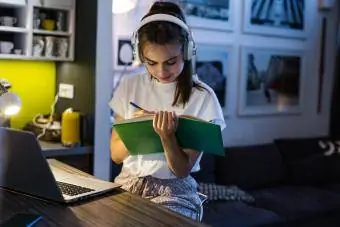 Tonårsflicka som studerar medan hon bär brusreducerande hörlurar