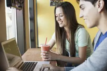 Dua remaja belajar di laptop dengan smoothie