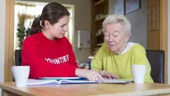 frivillig hjælper en senior kvinde med papirarbejde