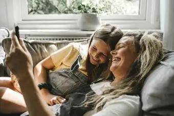 Mami dhe vajza duke qeshur në divan